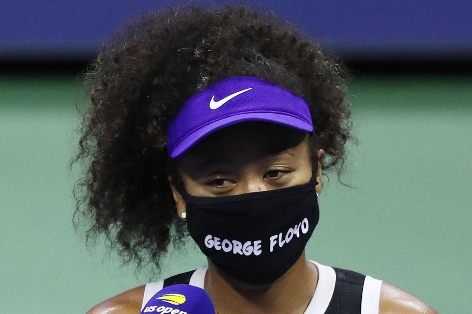 Naomi Osaka wears a mask that says George Floyd near a microphone.