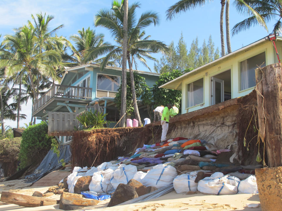 Sandbags are piled up in front of properties damaged by severe beach erosion in the Rocky Point neighborhood of Oahu's North Shore in Haleiwa, Hawaii on Tuesday, Dec. 31, 2013. Some property owners want to be able to install a seawall or something similar to protect their property, but scientists say doing so could lead the sand on the nearby coastline _ including Sunset Beach, home to some of the world’s top surfing contests _ to disappear. (AP Photo/Audrey McAvoy)