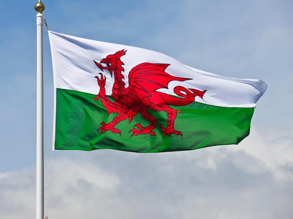 The welsh flag, a red dragon on a green and white background, flutters in the wind against a blue sky. (Getty Images/iStockphoto)