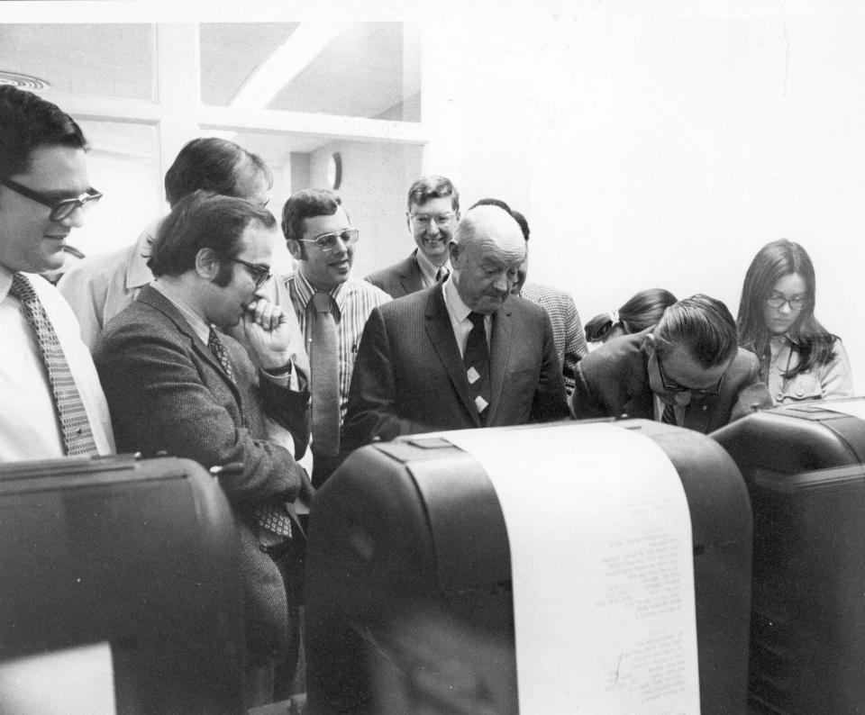 Beacon Journal editors and staffers gather at teletype machines as the Associated Press announces the Pulitzer on May 3, 1971. Pictured are Tim Smith, Abe Zaidan, Ben Maidenburg, Bob Giles, Ray Redmond, John S. Knight, Al Fitzpatrick, Bill Schlemmer and Kathy Lilly.
