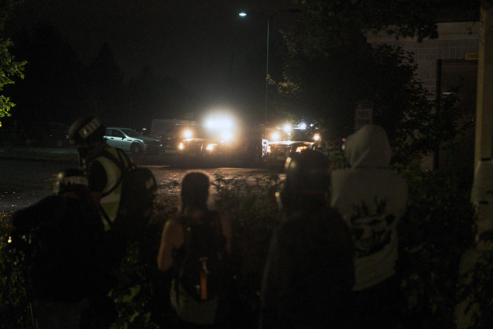 Manifestantes se congregan en Portland, Oregon, mientras policías los observan desde sus patrullas, el 30 de agosto de 2020. (Mason Trinca/The New York Times)