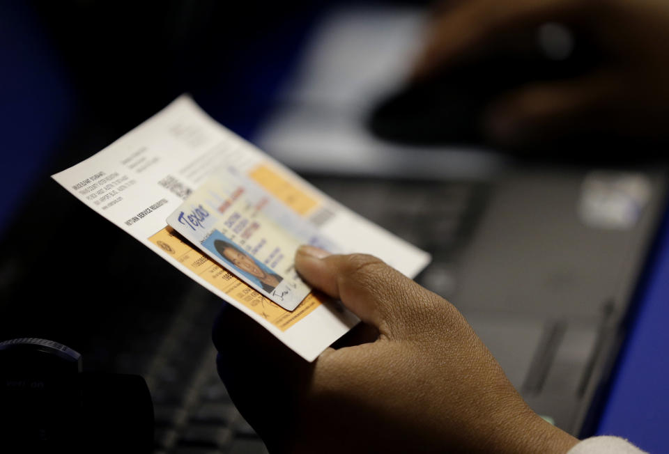 FILE - An election official checks a voter's photo identification at an early voting polling site in Austin, Texas, on Feb. 26, 2014. A U.S. Supreme Court decision a decade ago that tossed out the heart of the Voting Rights Act continues to reverberate across the country. Republican-led states continue to pass voting restrictions that, in several cases, would have been subject to federal review had the court left the provision intact. (AP Photo/Eric Gay, File)