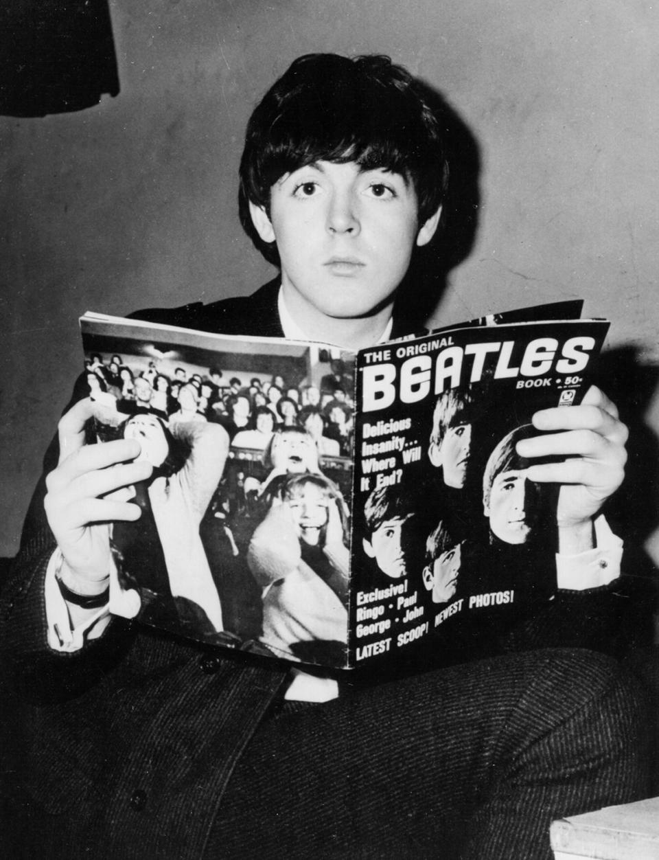 <p>Holding a Beatles fan magazine in 1964. </p>