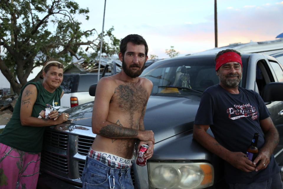 From left, Nora Rodrigue, her son, Brent Rodrigue Jr., and Glynn Chaisson lean on a truck where they are now sleeping after their homes were destroyed by Hurricane Ida in Chauvin, La., on Monday, Sept. 27, 2021. (AP Photo/Jessie Wardarski)