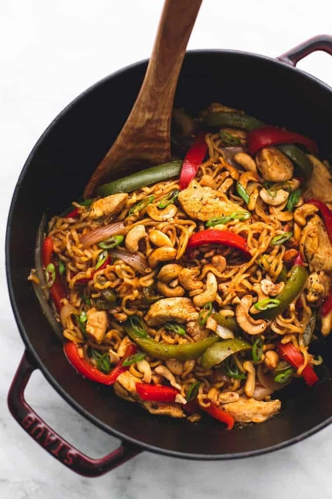 A skillet of ramen noodles stir-fried with chicken, cashews, and peppers