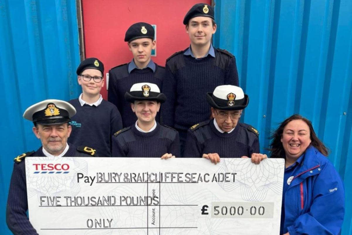 Sub-lieutenant Longley of the Sea Cadets (front left) receives a cheque from Tesco Bury Community Champion Wendy Howarth (front right). <i>(Image: Tesco Prestwich)</i>
