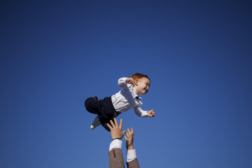 A Muslim man playfully tosses a toddler into the air at the end of Eid al-Fitr prayers in Bucharest, Romania, April 10, 2024. (AP Photo/Andreea Alexandru)