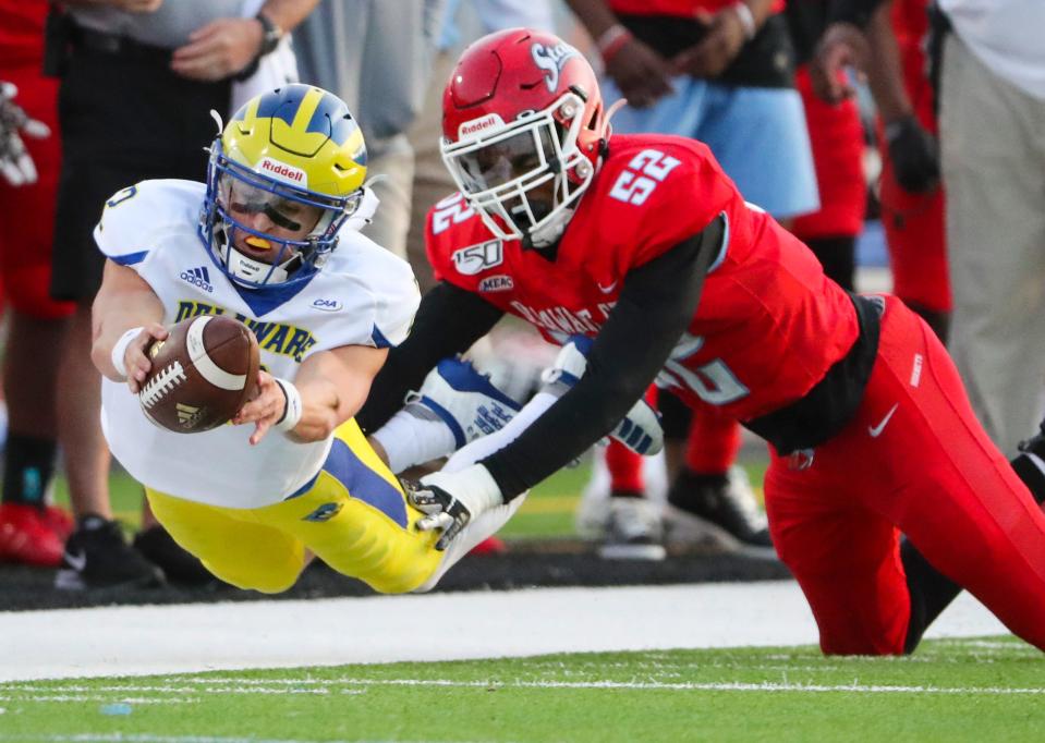 Delaware quarterback Nolan Henderson dives to try to reach a first down on a second quarter scoring drive as Delaware State's Ahmed Bailey tackles him at Alumni Stadium in Dover Saturday, April 10, 2021.