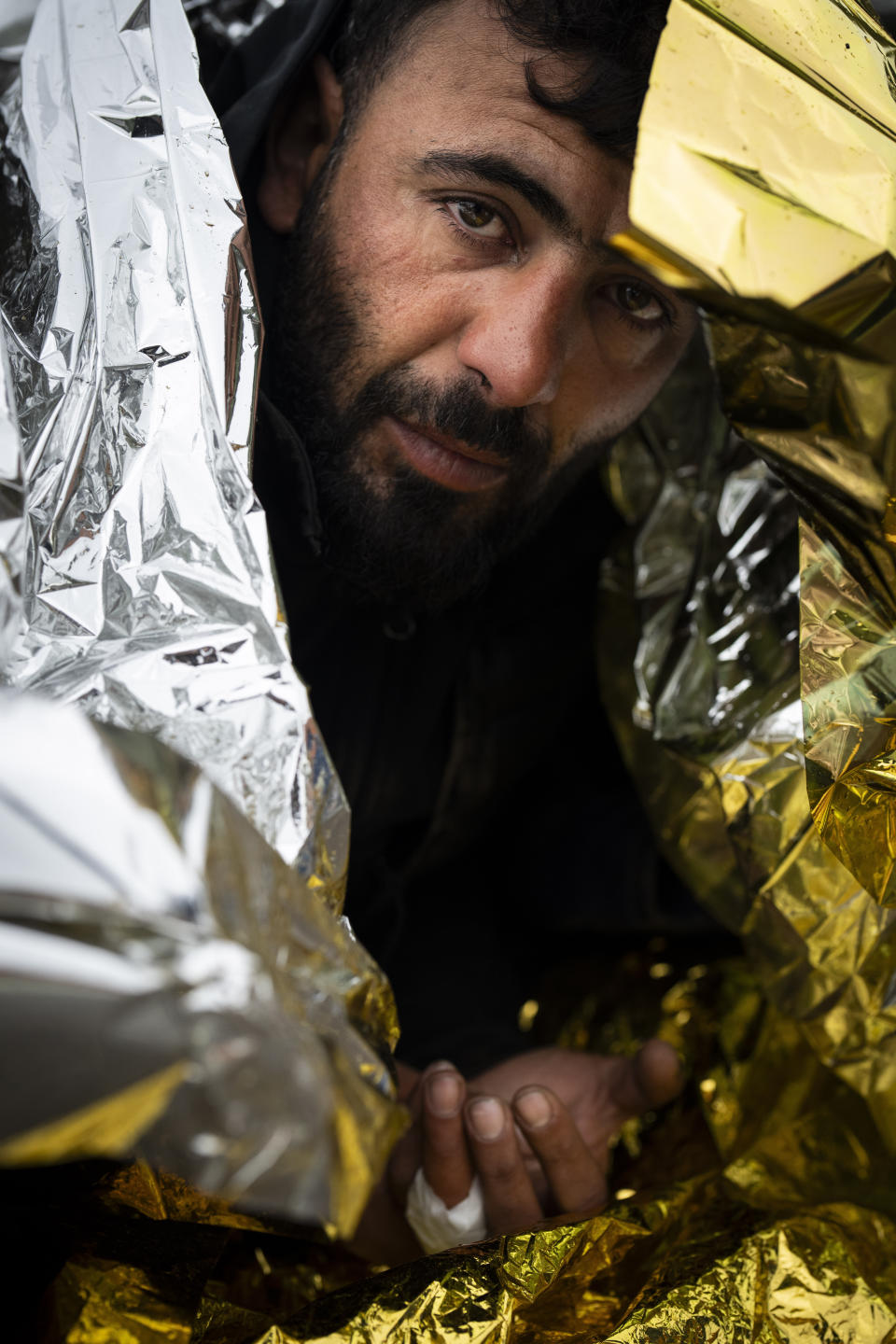 Wrapped in an emergency blanket to regain body heat, a migrant from Iraqi Kurdistan is seen on a street in Ambleteuse, northern France, on Saturday, May 18, 2024, after being spotted by the police while attempting to cross by boat to the United Kingdom. (AP Photo/Bernat Armangue)