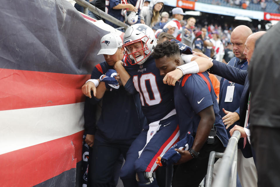 New England Patriots quarterback Mac Jones (10) is helped off the field after suffering a leg injury with less than two minutes to play in the second half of an NFL football game against the Baltimore Ravens, Sunday, Sept. 25, 2022, in Foxborough, Mass. (AP Photo/Michael Dwyer)