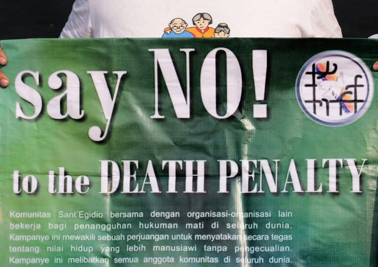 A protester holds a banner during a demonstration against the death penalty in front of the presidential palace in Jakarta on July 26, 2016