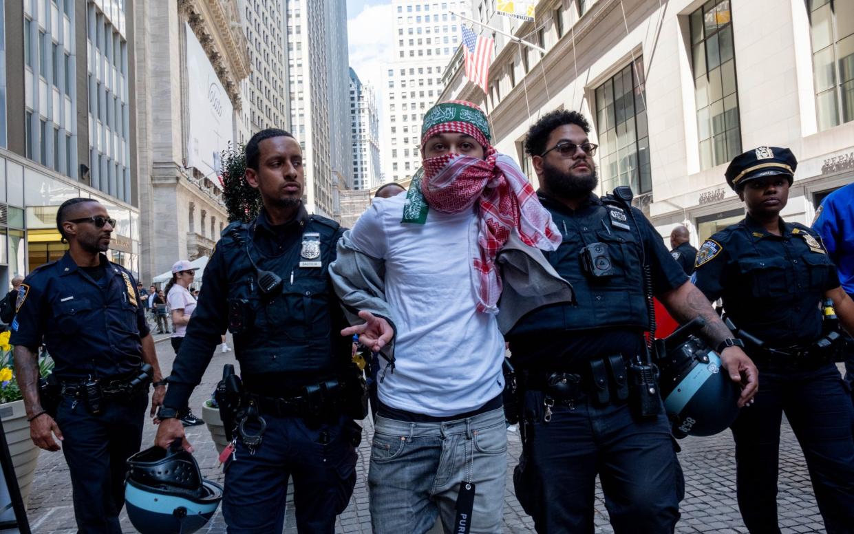 A protester with a green pro-Palestinian headband is arrested on Wall Street in New York