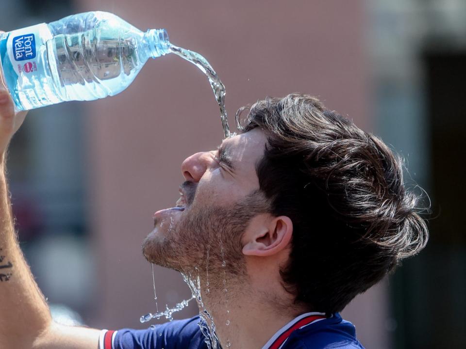 A man drops water on his forehead from a plastic bottle.