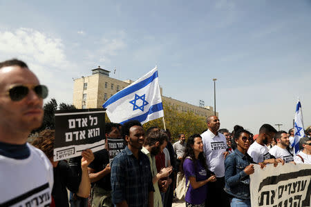 FILE PHOTO: African migrants and Israeli activists demonstrate in support of the new agreement with the U.N. refugee agency to relocate thousands of African migrants, outside Israeli Prime Minister office in Jerusalem April 3, 2018. The placard in Hebrew reads "Every Human is a Human". REUTERS/Ammar Awad