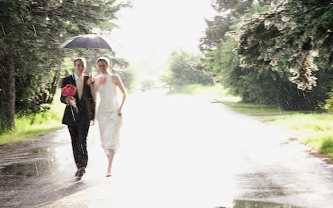 Bride and bridegroom walking through rain - Credit: Corbis RF Stills