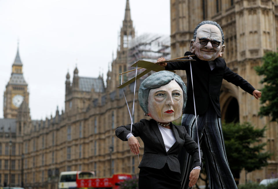 Performers pose outside the Houses of Parliament, wearing puppet heads of media mogul Rupert Murdoch and Britain's Prime Minister Theresa May.