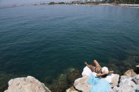 A woman sunbathes during a heatwave at a beach, in Alimos suburb, southern Athens, Greece, Monday, Aug. 2, 2021. The heat wave is expected to peak Monday, with temperatures inland ranging from 42 to 46 degrees Celsius (107.6 to 114.8 Fahrenheit). Temperatures will remain at 40 Celsius (104 Fahrenheit) or above in much of Greece until at least Friday, meteorologists say. (AP Photo/Michael Varaklas)