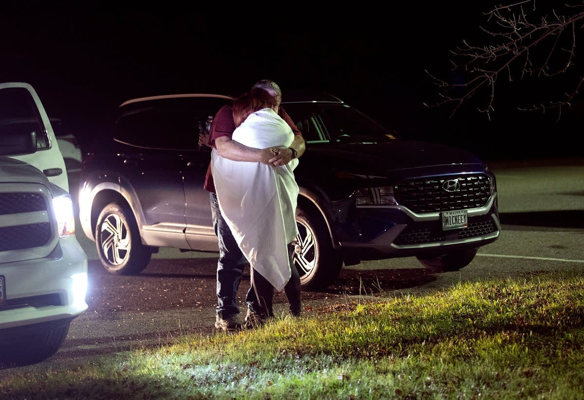 A woman is hugged by a man at a reunification centre at Auburn Middle School (AP)