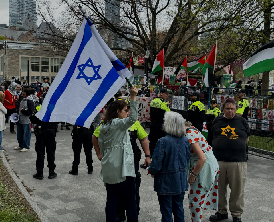 <p>Protester holds Israeli flag outside the U of T encampment. (Credit: Corné van Hoepen)</p> 