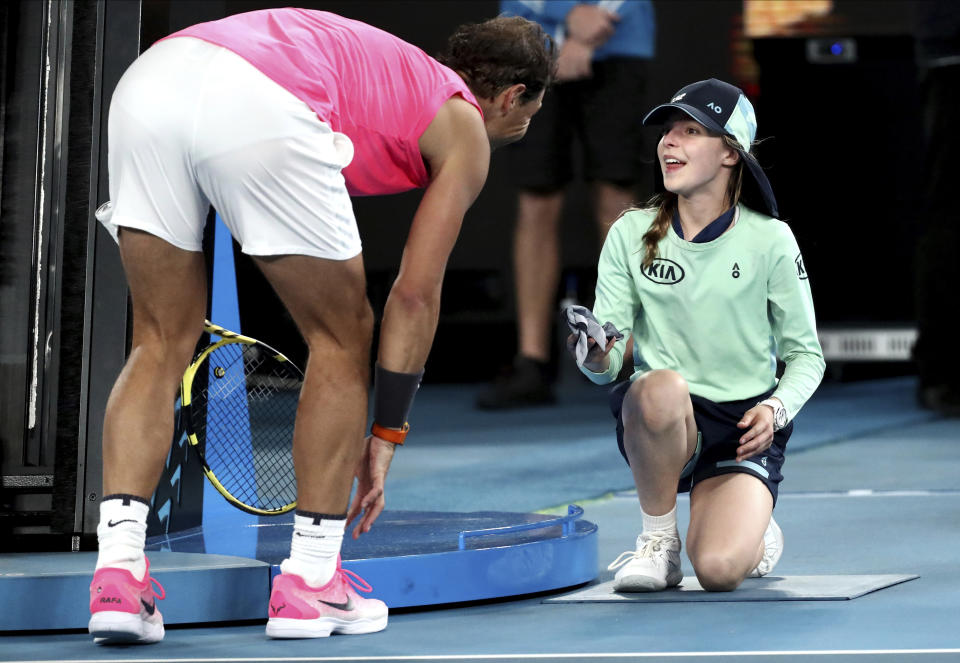 Spain's Rafael Nadal hands a ball girl his bandana after a ball hit her during his second round match against Federico Delbonis of Argentina at the Australian Open tennis championship in Melbourne, Australia, Thursday, Jan. 23, 2020. (AP Photo/Dita Alangkara)