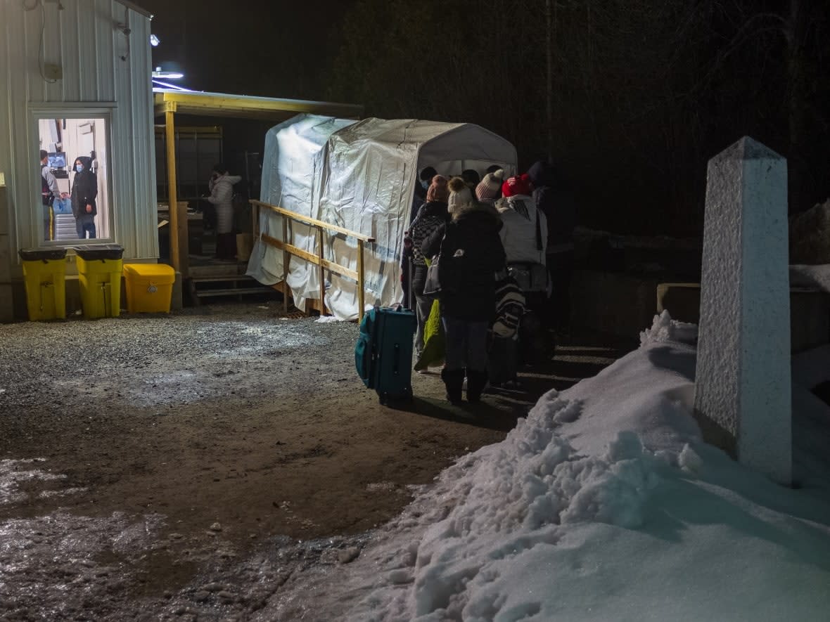 Asylum seekers are shown being processed at the RCMP's temporary post at the irregular border crossing at the end of Roxham Road, on the Canada-U.S. border, in the early hours of March 16. (Craig Desson/CBC - image credit)