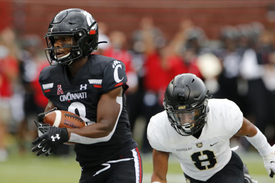 Cincinnati wide receiver Michael Young, left, scores a touch after a catch as Army defensive back Javhari Bourdeau defends during the first half of an NCAA college football game Saturday, Sept. 26, 2020, in Cincinnati, Ohio. (AP Photo/Jay LaPrete)