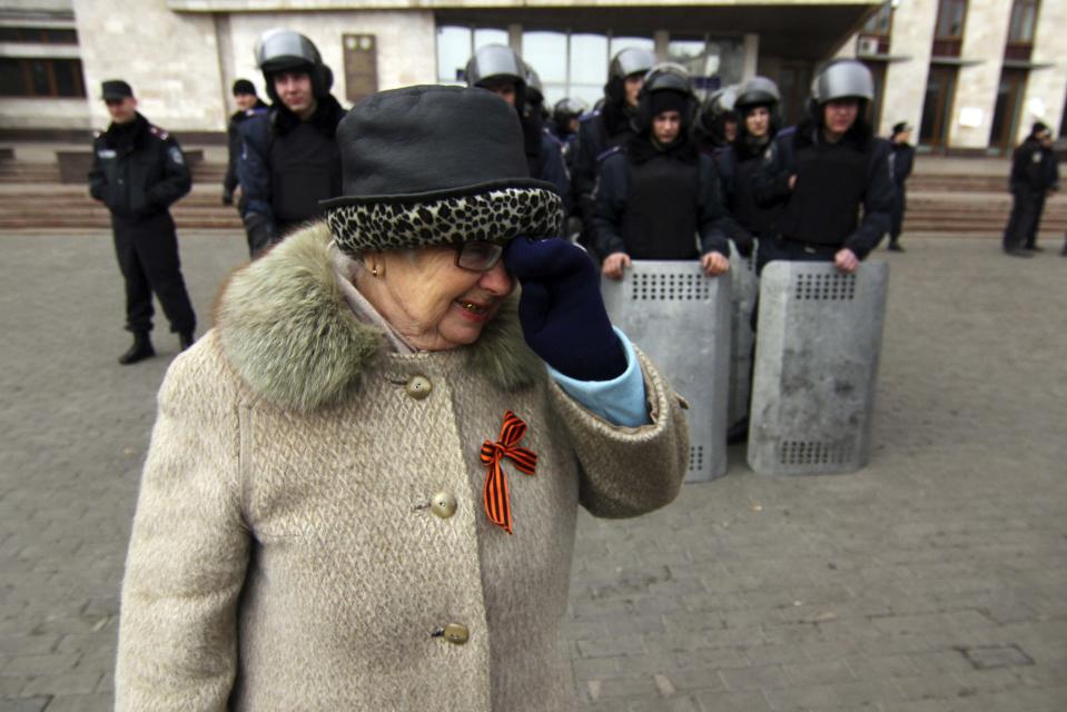 A woman wearing a pro-Russian ribbon walks near Ukrainian police officers outside the regional administration building in the eastern Ukrainian city of Donetsk