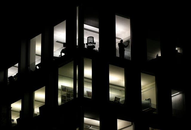 A solitary employee stands by a window while speaking on a phone in an otherwise empty office building on Blackfriars Road (Jonathan Brady/PA)