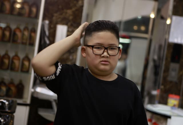 To Gia Huy, nine checks his hair after having a Kim Jong Un haircut in Hanoi, Vietnam