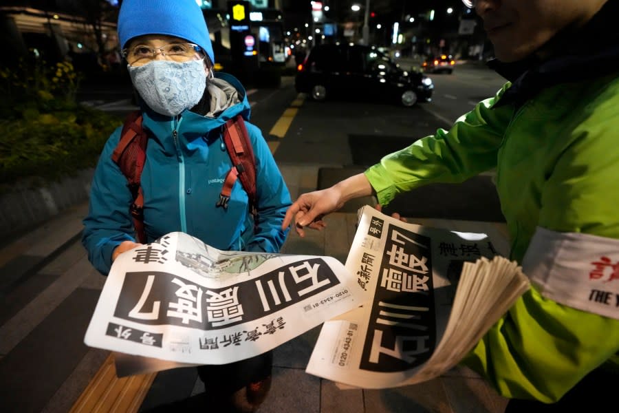 People receive extra edition of Yomiuri Shimbun newspaper reporting the earthquakes Monday, Jan. 1, 2024 in Tokyo. Japan issued tsunami alerts and ordered evacuations following a series of earthquakes on Monday that started a fire and trapped people under rubble on the west coast of its main island. The headline reads ” Ishikawa, earthquake intensity 7.” (AP Photo/Shuji Kajiyama)