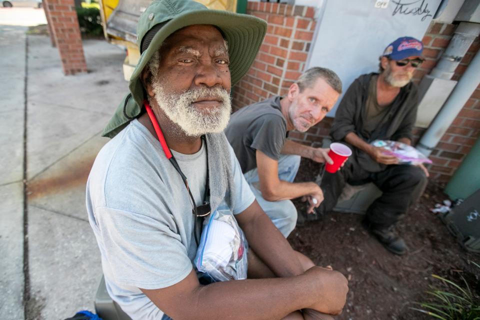 Calvin Cooper, left, Leif, and Alan Wilson get some shade at a convenience store as the Grace Marketplace Street Team delivers drinks and sandwiches to homeless people in Northwest Gainesville on Aug. 14, 2023.