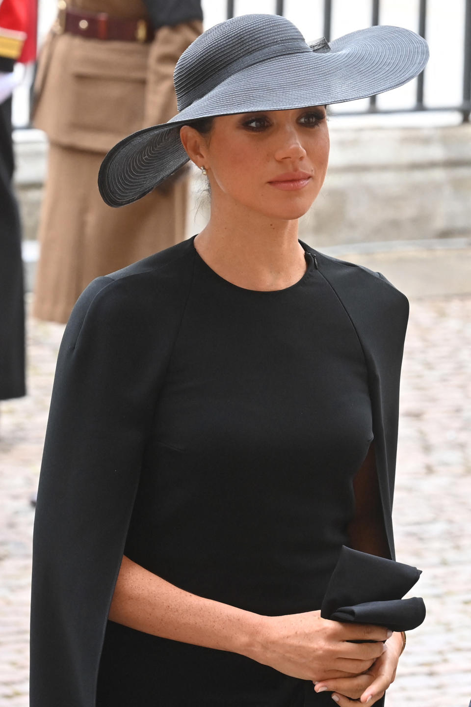 Meghan wears a black dress and black hate as she arrives at Westminster Abbey in London