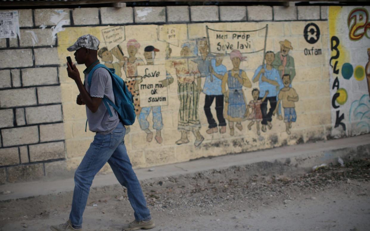 A man walks past an Oxfam sign in Haiti - Reuters