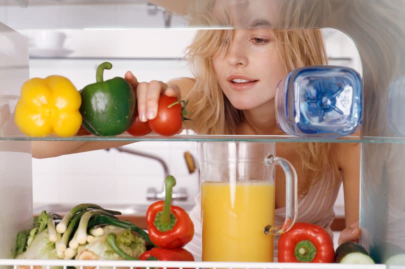 File photo. Woman Reaching For a Tomato in a Fridge