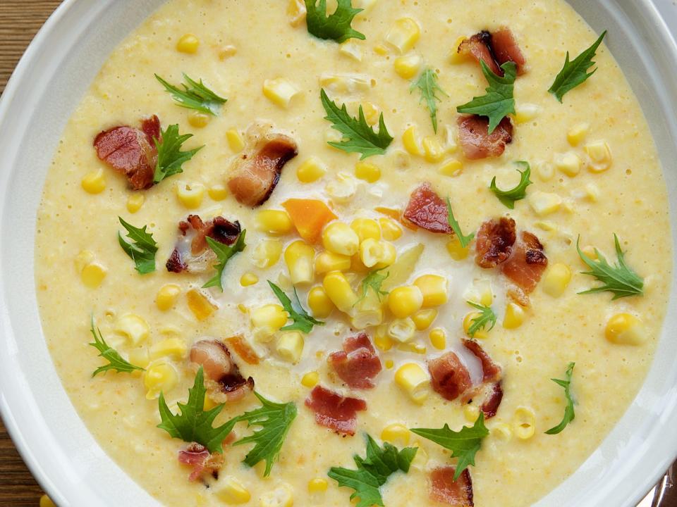 corn chowder with bacon on wooden background with spoon
