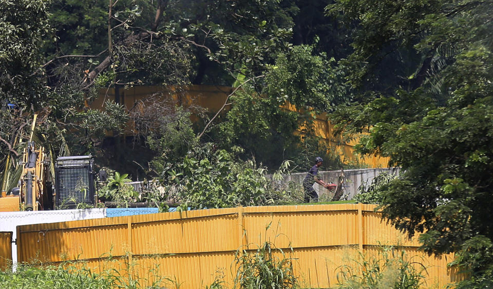 A man cuts a tree branch at the construction site of a metro train parking shed at Aarey Colony, Mumbai, India, Monday, Oct, 7, 2019. India's Supreme Court has ordered the government of the Indian state of Maharashtra to stop tree-felling after protesters swarmed the area. The court order on Monday stalls tree-cutting at least until another hearing October 21. (AP Photo/Rafiq Maqbool)