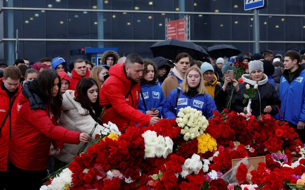 Một nhóm thanh niên Nga cắm thêm hoa trên đống hoa hồng khổng lồ vào một ngày xám xịt