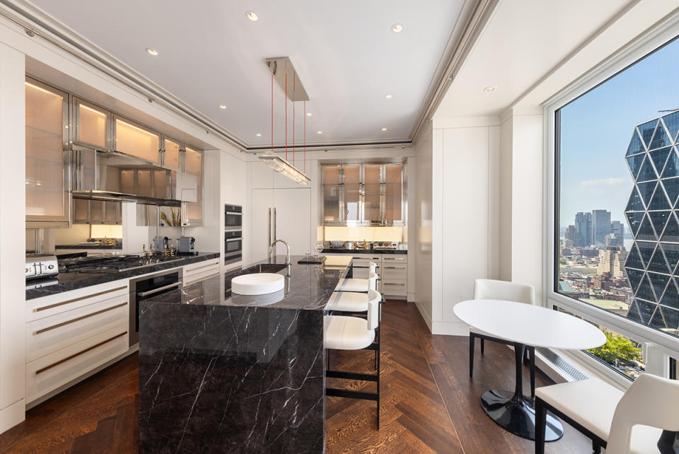 Black granite counters waterfall over the ends of the island in the spacious gourmet kitchen.