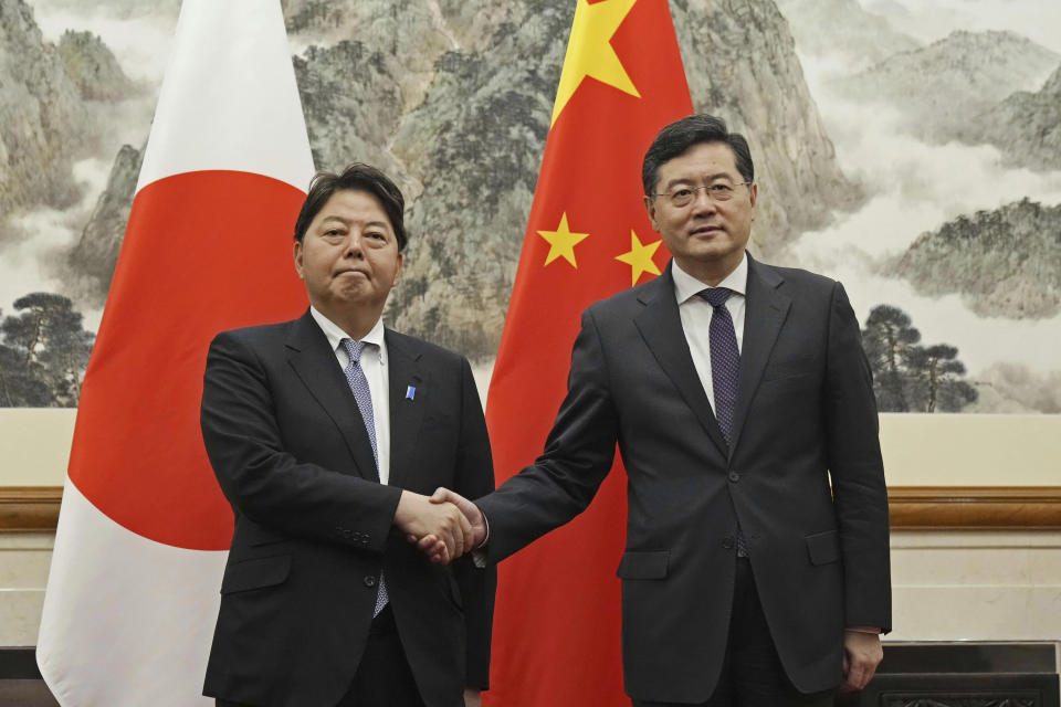 Japanese Foreign Minister Yoshimasa Hayashi, left, shakes hands with his counterpart Qin Gang at the Diaoyutai State Guest House in Beijing Sunday, April 2, 2023. (Kyodo News via AP)