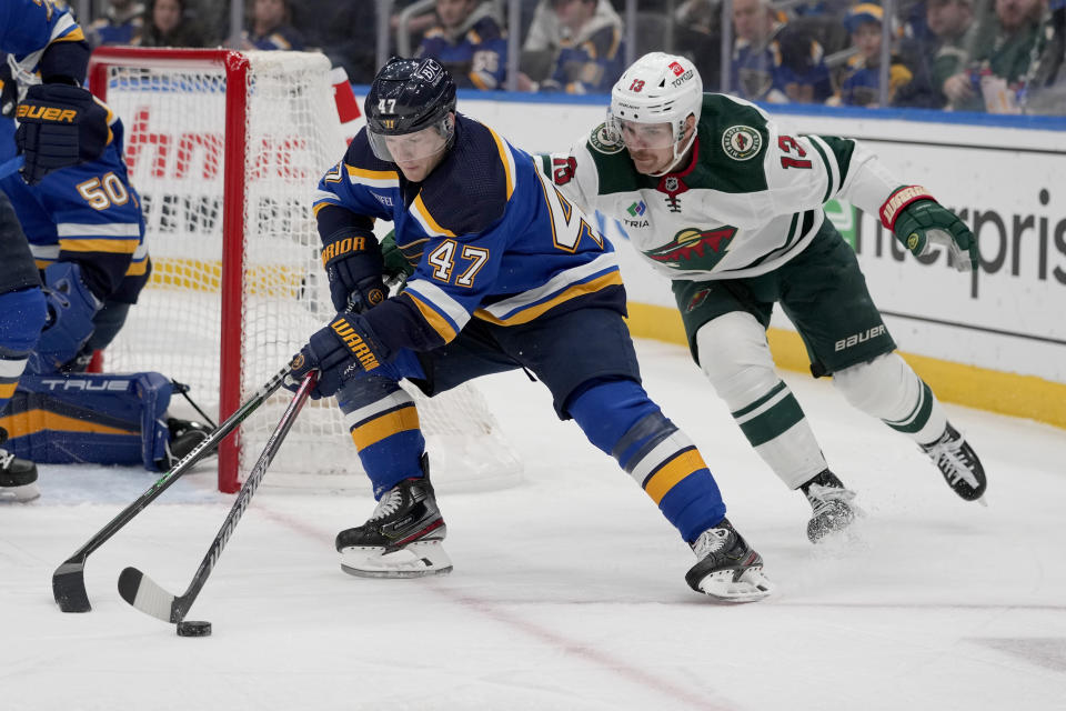 St. Louis Blues' Torey Krug (47) reaches for a loose puck as Minnesota Wild's Sam Steel (13) defends during the first period of an NHL hockey game Wednesday, March 15, 2023, in St. Louis. (AP Photo/Jeff Roberson)