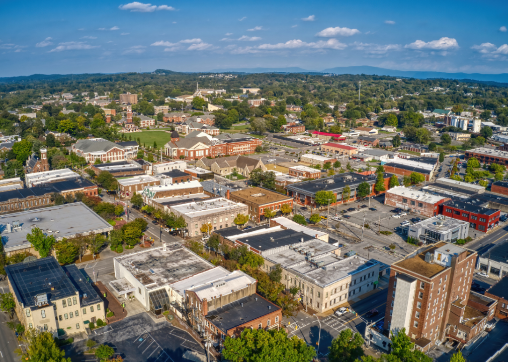 Aerial view of a city with green trees and mountains in the far background. 