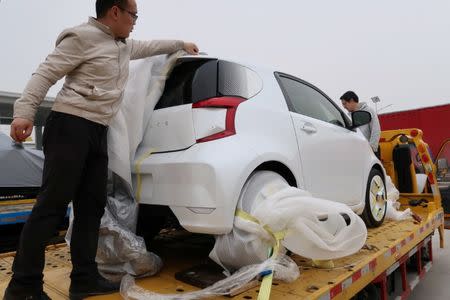 Singulato workers unwrap a concept car, dubbed the iC3, which is based on a discontinued EV of Toyota, in preparation for the upcoming auto show in Shanghai, China April 14, 2019. REUTERS/Norihiko Shirouzu