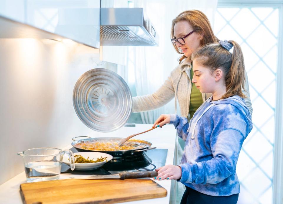 side view of mother and daughter cooking at stove with smoke in kitchen