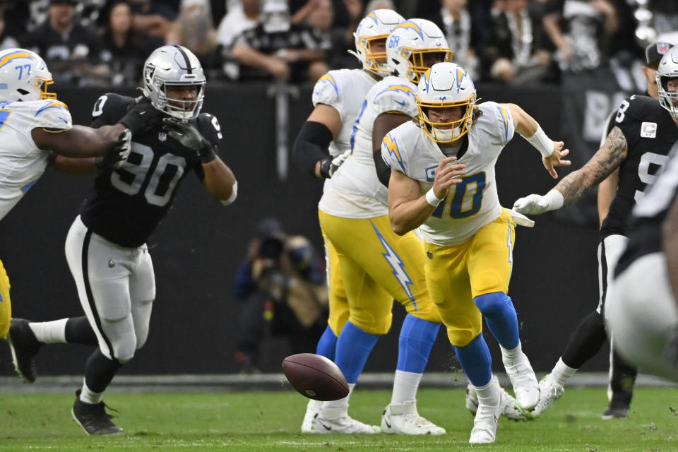 Los Angeles Chargers quarterback Justin Herbert (10) chases down his own fumble under pressure from Las Vegas Raiders defensive tackle Jerry Tillery (90) during the first half of an NFL football game, Sunday, Dec. 4, 2022, in Las Vegas. (AP Photo/David Becker)