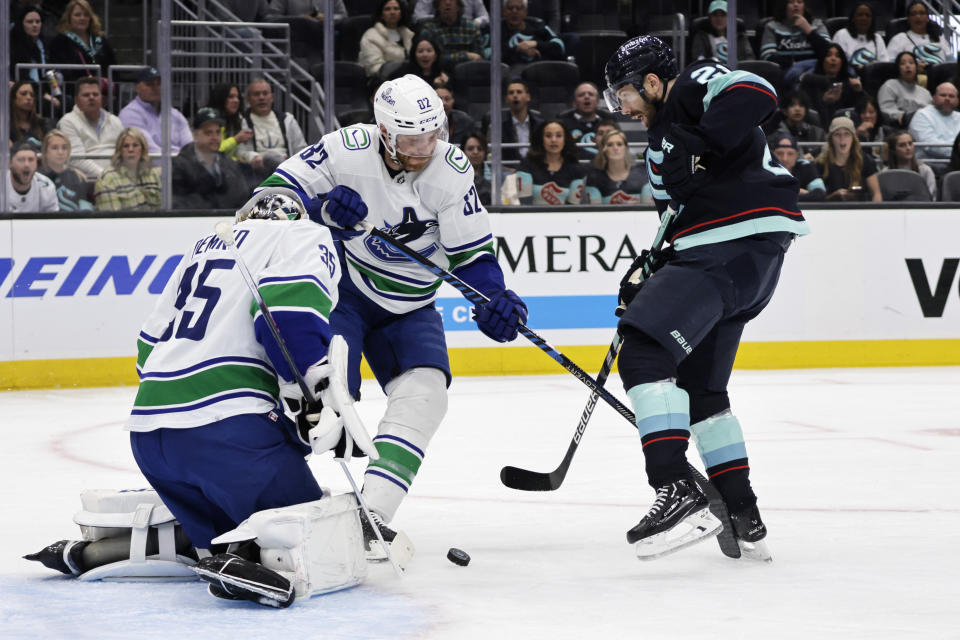 Seattle Kraken center Alex Wennberg, right, tries to shoot, but is blocked by Vancouver Canucks goaltender Thatcher Demko, left, with defenseman Ian Cole helping Demko during the first period of an NHL hockey game Thursday, Feb. 22, 2024, in Seattle. The Kraken won 5-2. (AP Photo/John Froschauer)