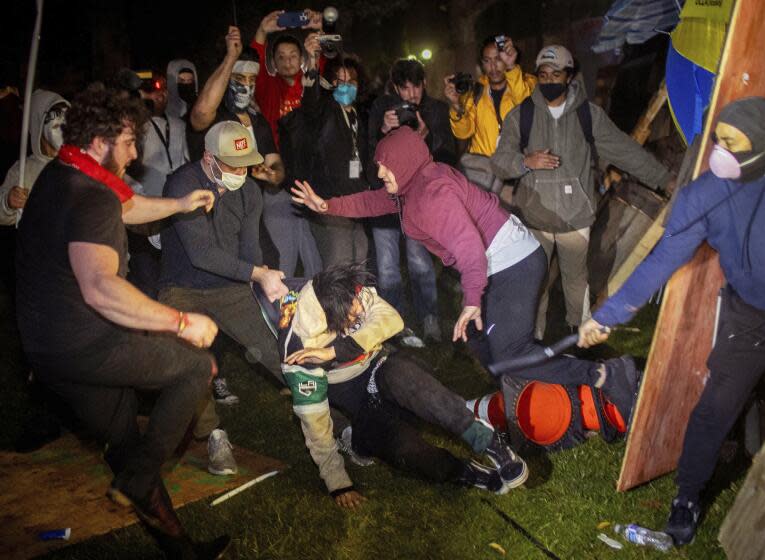 Demonstrators clash at an encampment at UCLA early Wednesday, May 1, 2024, in Los Angeles. Dueling groups of protesters have clashed at the University of California, Los Angeles, grappling in fistfights and shoving, kicking and using sticks to beat one another. (AP Photo/Ethan Swope)