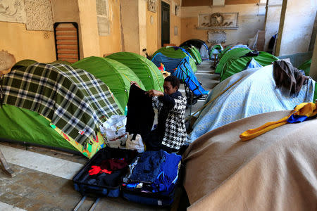 A woman folds clothes next to her tent in the portico of the Basilica of the Santi Apostoli, where she lives after being evicted from an unused building along with other families in August 2017, in Rome, Italy January 29, 2018. REUTERS/Tony Gentile