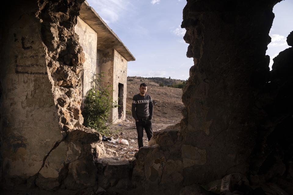 A Syrian migrant stands outside an abandoned army outpost near Ieropigi village, northern Greece, at the Greek - Albanian border, on Tuesday, Sept. 28, 2021. A relatively smooth section of Greece's rugged border with Albania is turning into a major thoroughfare north for migrants in Greece seeking a better life in Europe's prosperous heartland. (AP Photo/Giannis Papanikos)