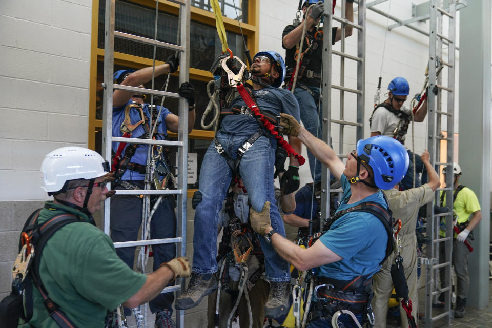 Sergio Cordova, center, plays the victim so classmates can learn how to deal with someone injured on an off shore wind turbine during a Global Wind Organisation certification class at the Massachusetts Maritime Academy in Bourne, Mass., Tuesday, Aug. 2, 2022. At the 131-year-old maritime academy along Buzzards Bay, people who will build the nation's first commercial-scale offshore wind farm are learning the skills to stay safe while working around turbines at sea. (AP Photo/Seth Wenig)