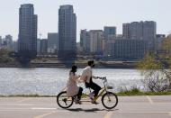 A couple wearing masks to protect against contracting the coronavirus disease (COVID-19) ride on a bicycle at a Han River Park in Seoul